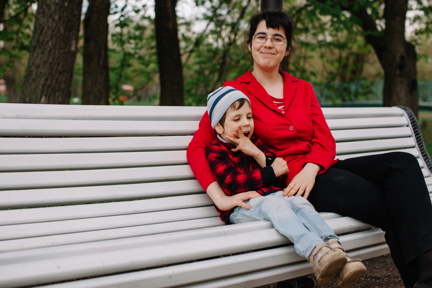 Woman sitting on bench with child with cerebral palsy